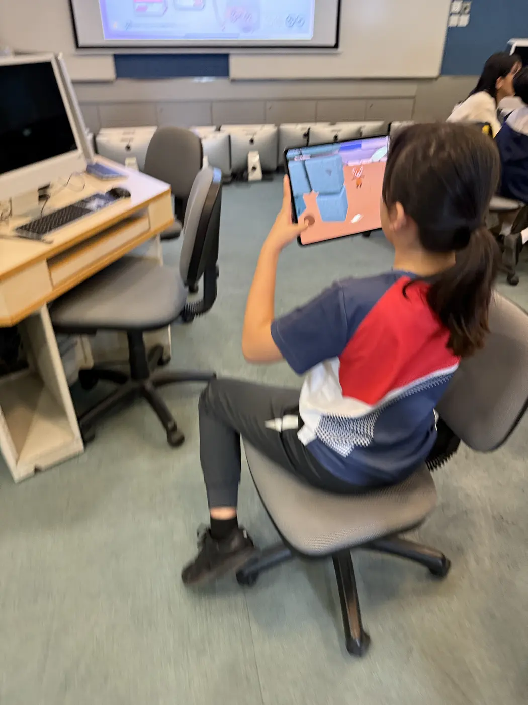 A student holding up an iPad to view their Wonderland scene in AR
